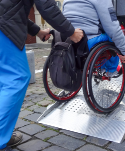 Man pushing another person in a wheel chair up a ramp