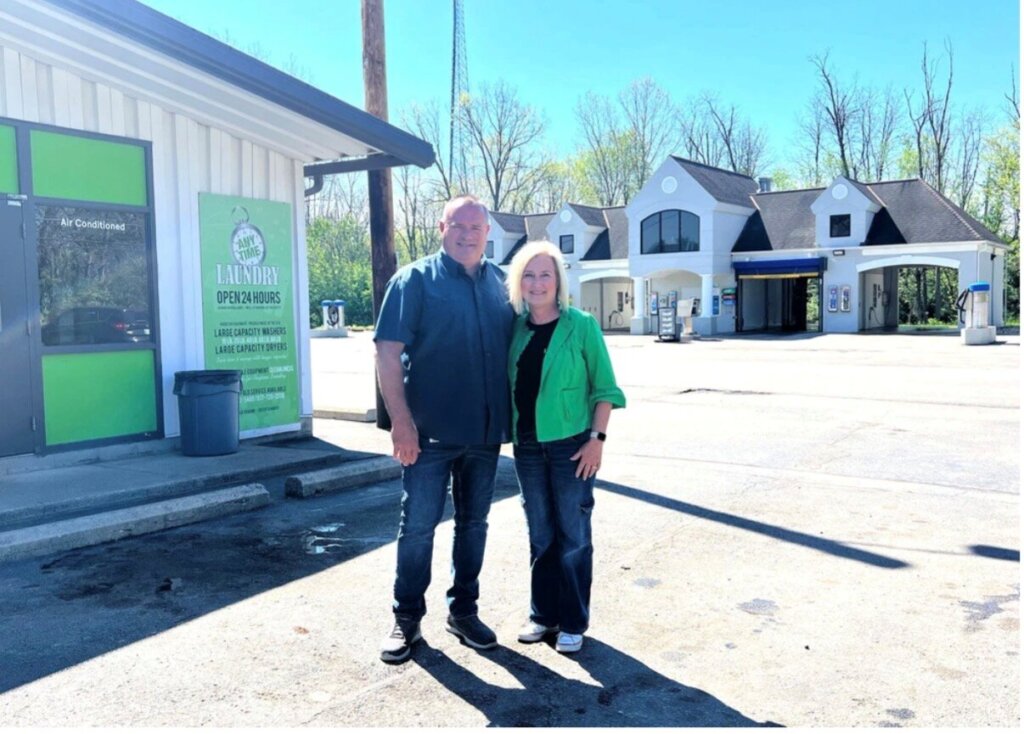 Two people smiling and standing in front of the laundry center