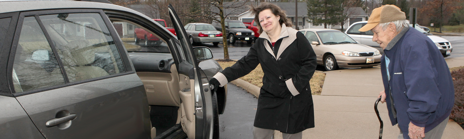 woman opens car door for elderly man